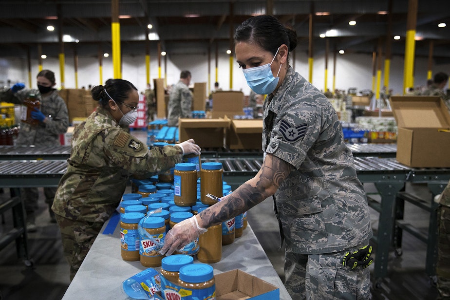 caption: Washington National Guard soldier Dahdia Hicks stacks jars of peanut butter on Tuesday, April 21, 2020, at a new emergency response center set up by Food Lifeline as a result of the growing need for food in Washington prompted by the coronavirus outbreak, along East Marginal Way South in Seattle. According to a Food Lifeline press release, the need has nearly doubled since the Covid-19 outbreak began while food donations have dropped by 70%.
