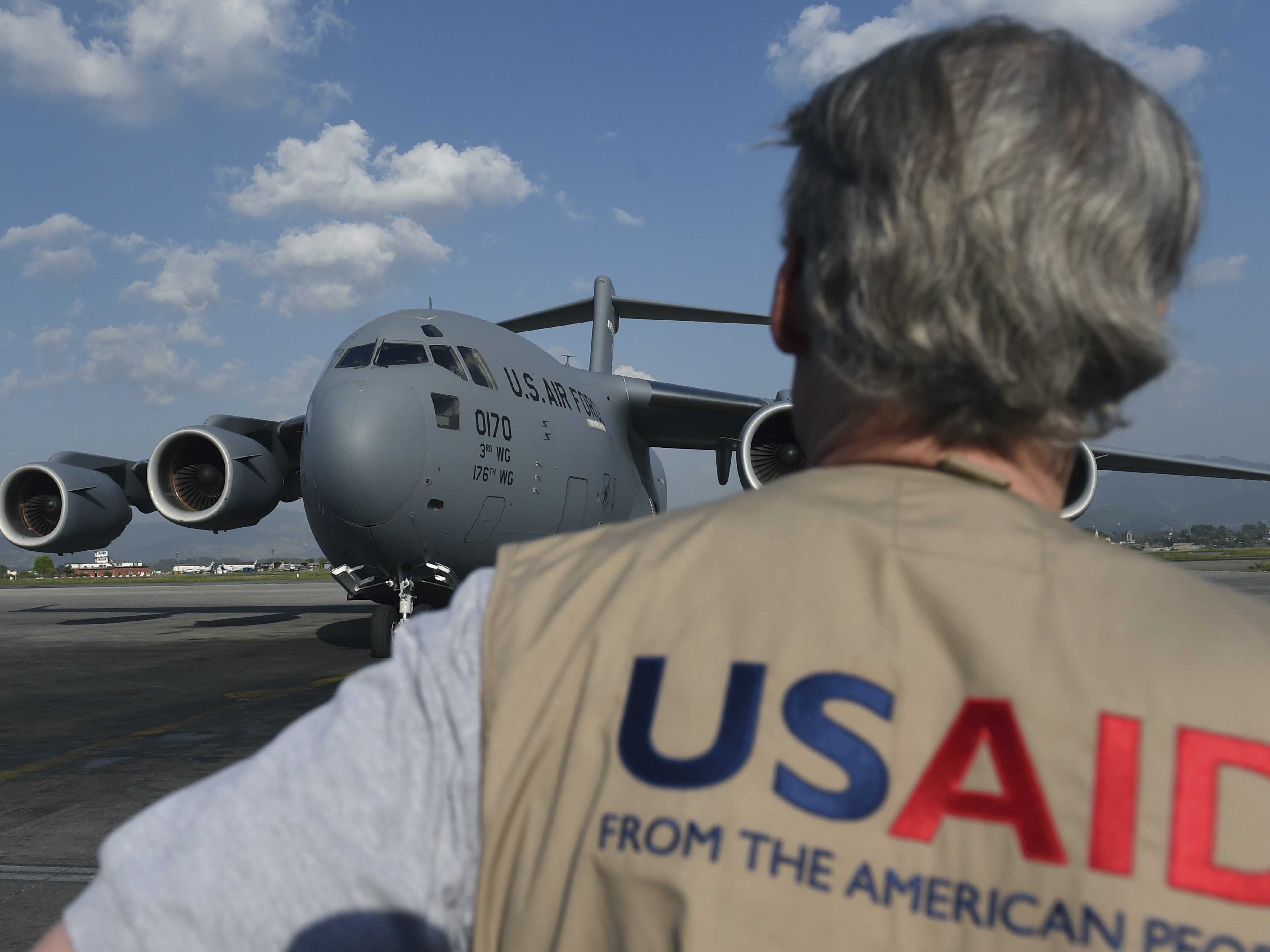 caption: A USAID officer watches as a U.S. military cargo plane taxis to a stop at Kathmandu's international airport in the wake of the 2015 earthquake. The agency funds projects that aim to alleviate poverty and disease and meet humanitarian needs around the world.