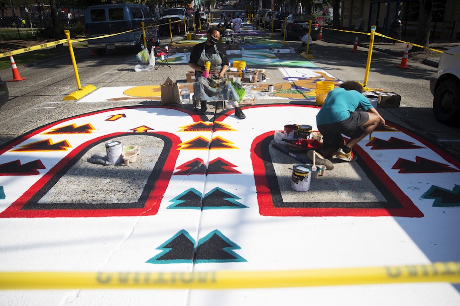 caption: Local artist Kimisha Turner, center, takes a break from painting the letter B in the Black Lives Matter street mural on Friday, October 2, 2020, on E. Pine Street in Seattle.