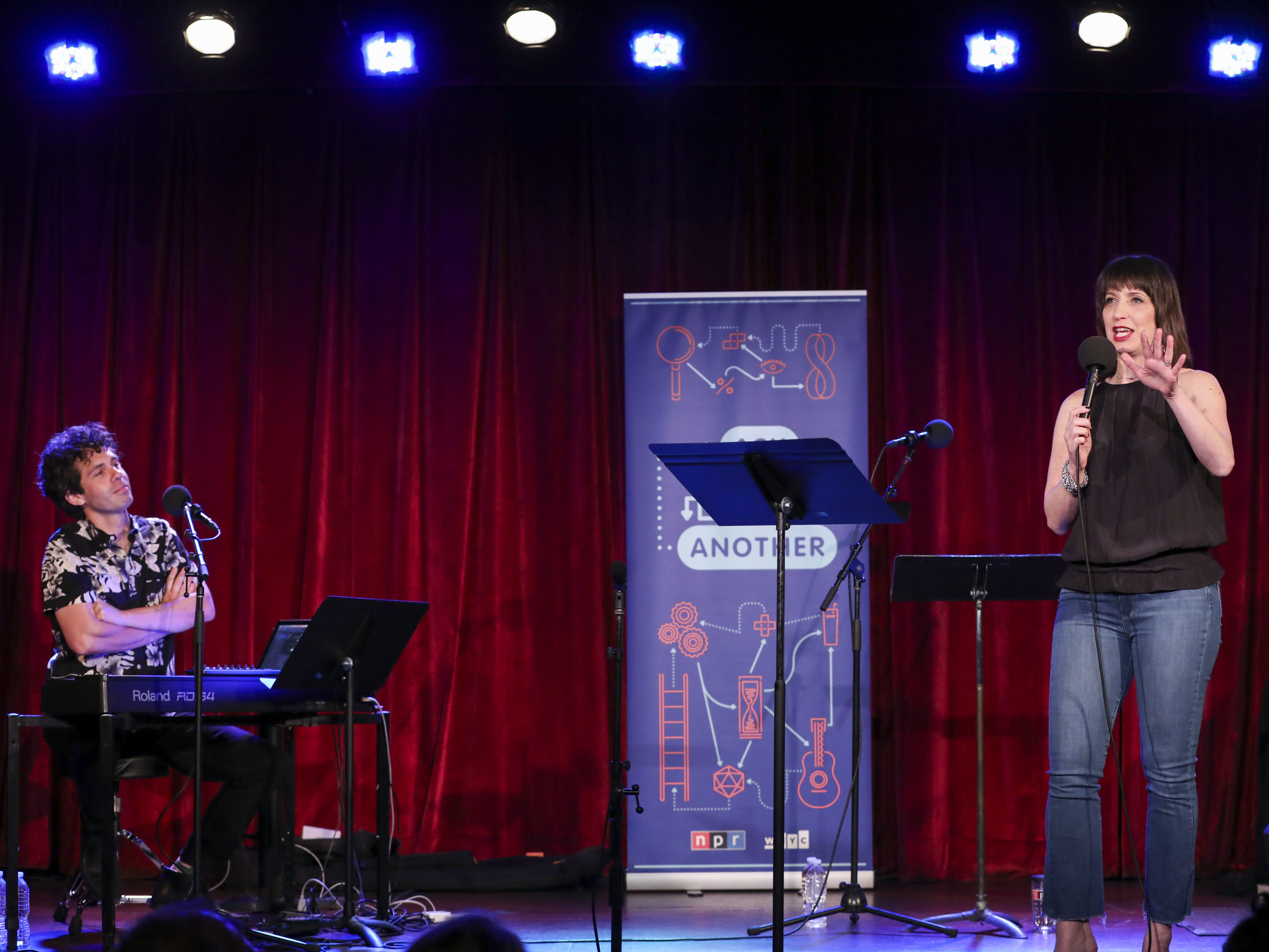 caption: Ophira Eisenberg performs on stage alongside Julian Velard on <em>Ask Me Another</em> at the Bell House in Brooklyn, New York.