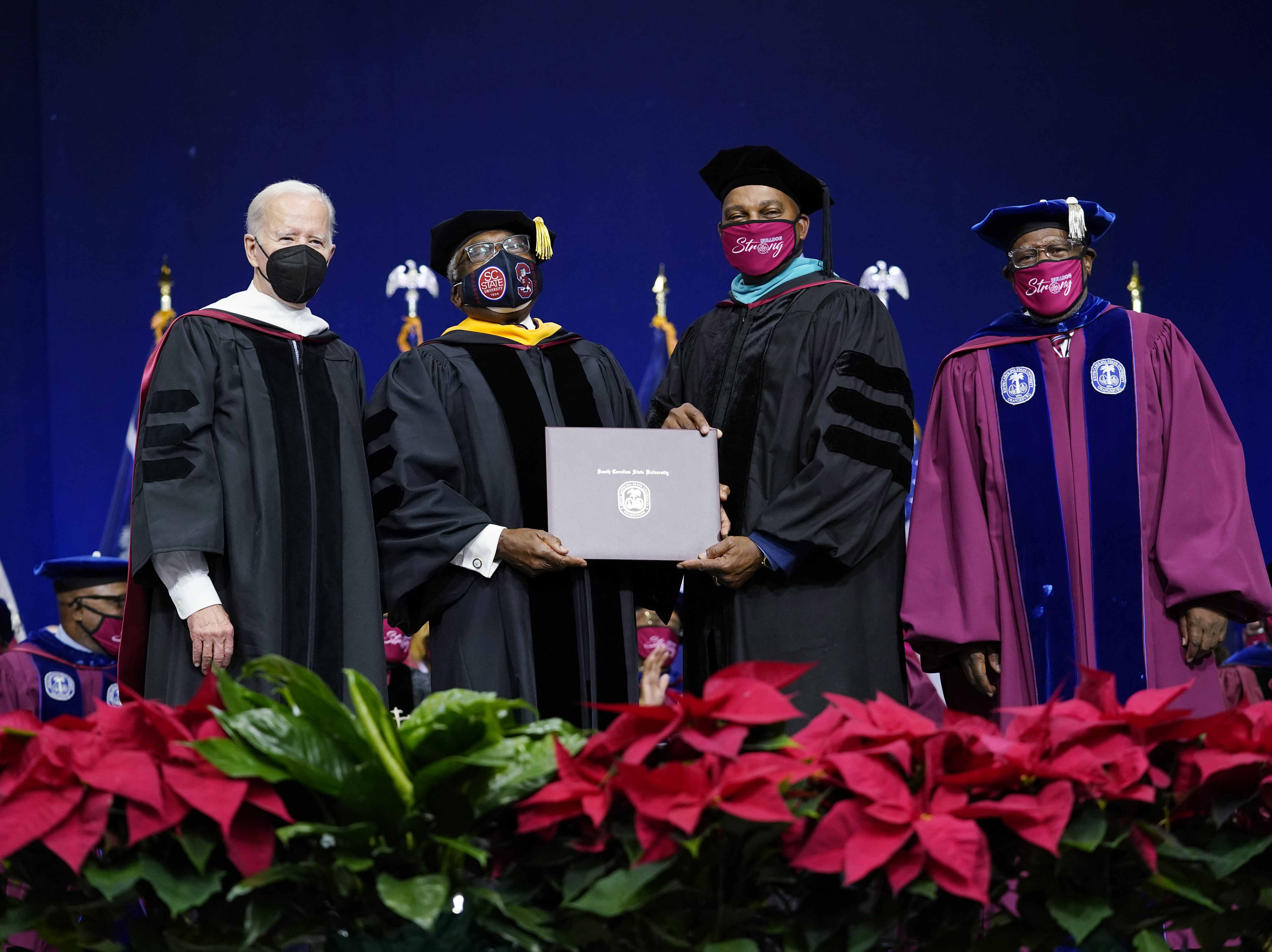 caption: Rep. Jim Clyburn, D-S.C., second from left, holds his history degree with South Carolina State University Interim President Alexander Conyers, second from right, on stage with President Joe Biden, left, and Rodney Jenkins, Chairman of the Board of Trustees, right, during the South Carolina State University's 2021 Fall Commencement Ceremony in Orangeburg, S.C., Friday, Dec. 17, 2021.