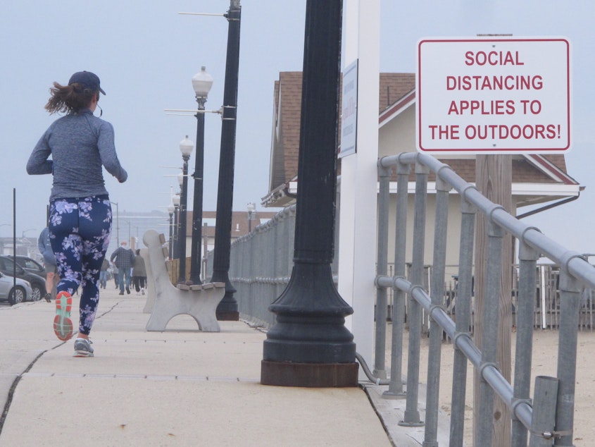 caption: A sign on the Bradley Beach, N.J., oceanfront urges people to practice social distancing even in the outdoors during the coronavirus outbreak. On Saturday, New Jersey Gov. Phil Murphy signed an executive order directing all residents to stay at home.
