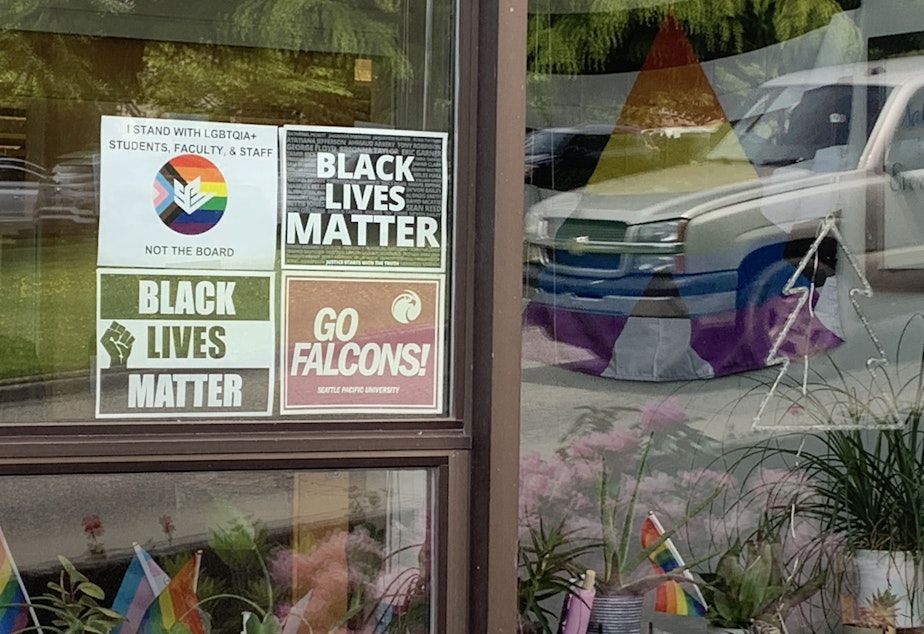 caption: A sign in solidarity with LGBTQIA+ students, faculty, and staff hangs in the window on Seattle Pacific University's campus.
