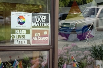 caption: A sign in solidarity with LGBTQIA+ students, faculty, and staff hangs in the window on Seattle Pacific University's campus.