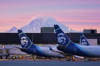 caption: Alaska Airlines planes parked at gates with Mount Rainier in the background at sunrise, on March 1, 2021, at Seattle-Tacoma International Airport in Seattle.