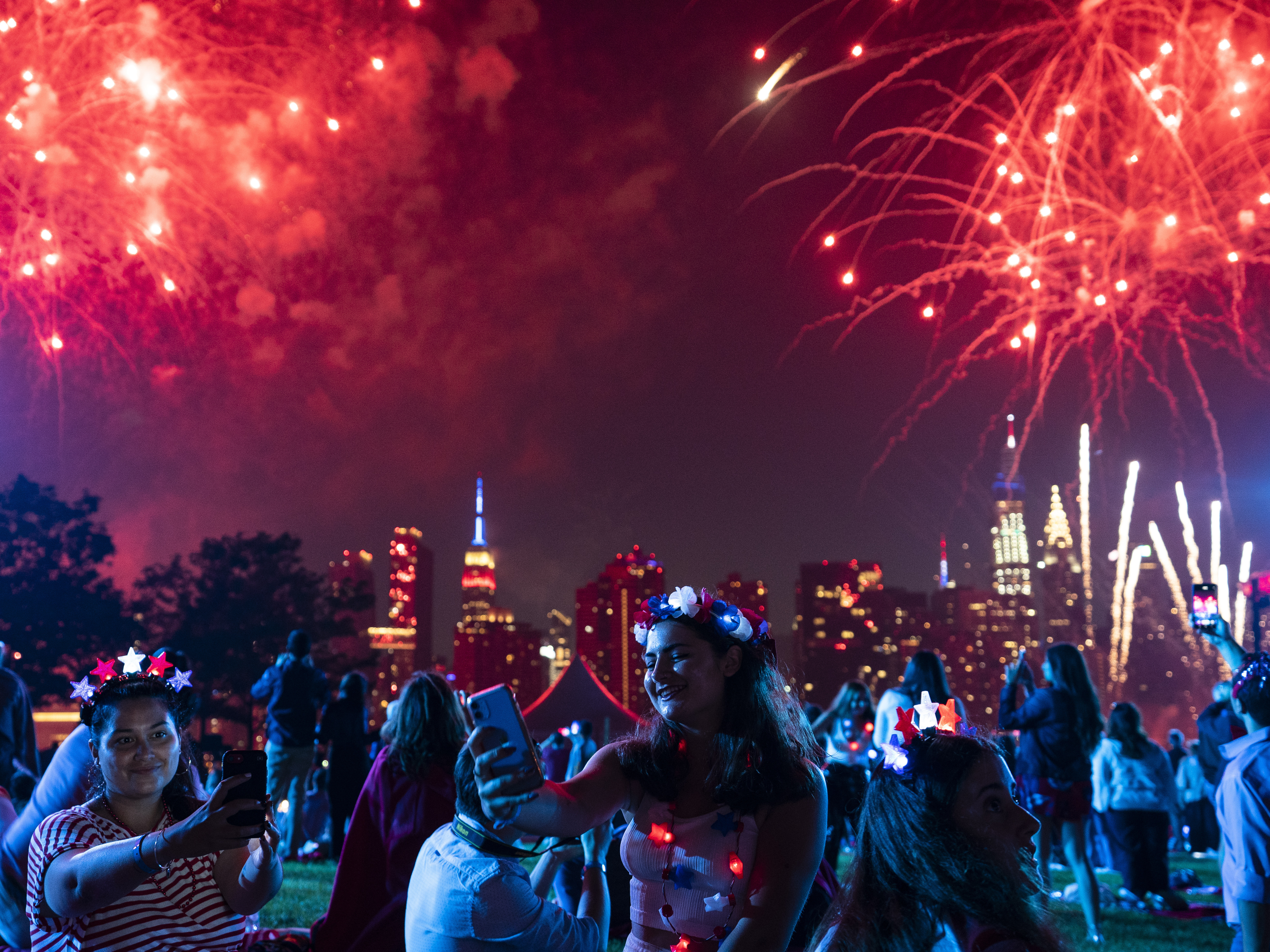 caption: Spectators watch as fireworks are launched over the East River and the Empire State Building in New York City on July 4, 2021. Regulators are warning people ahead of July Fourth to be careful handling any recreational fireworks.