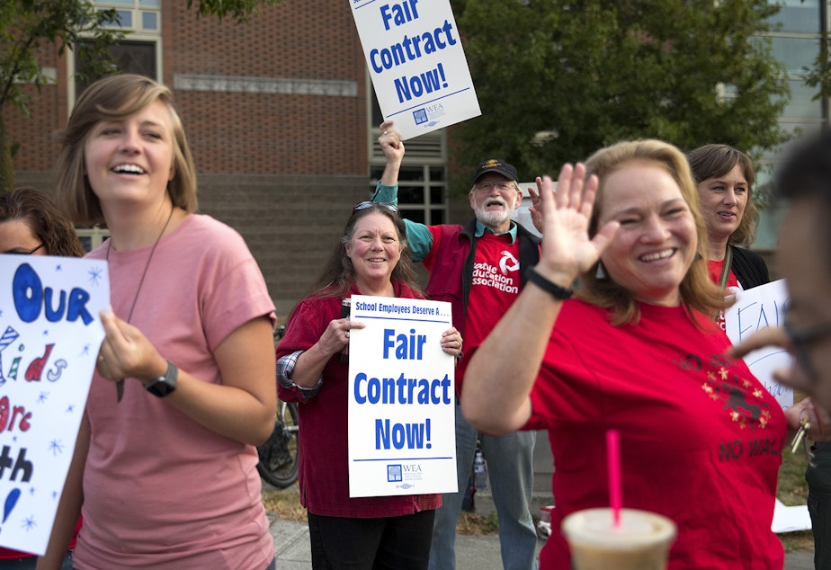 caption: Karen and Dewey Moody, center, cheer with others as a woman delivered coffee to picketing teachers on Wednesday, August 29, 2018, outside of Ballard High School in Seattle. 