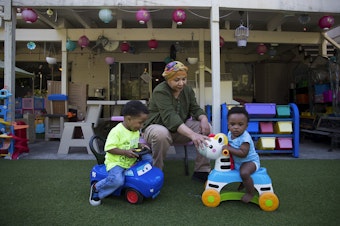 caption: Aqbal Kowaie, an overnight daycare employee, plays with 2-year-old Jaren Brown, left, and 10-month-old Avalon Brown, right, on Thursday, August 1, 2019, in Renton. 