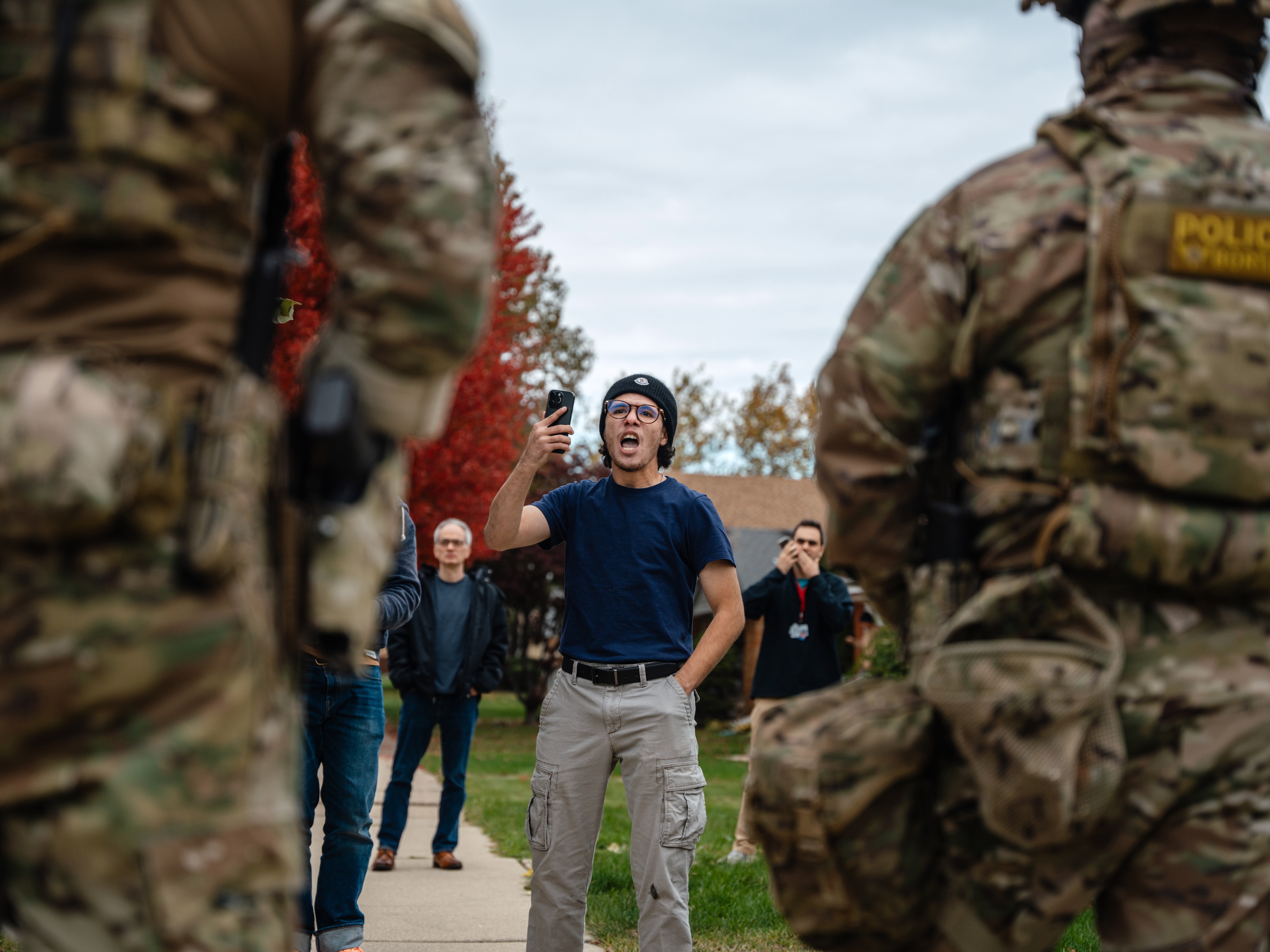caption: A young man confronts federal agents after they arrested a worker at a home in his Edison Park neighborhood on Friday in Chicago.