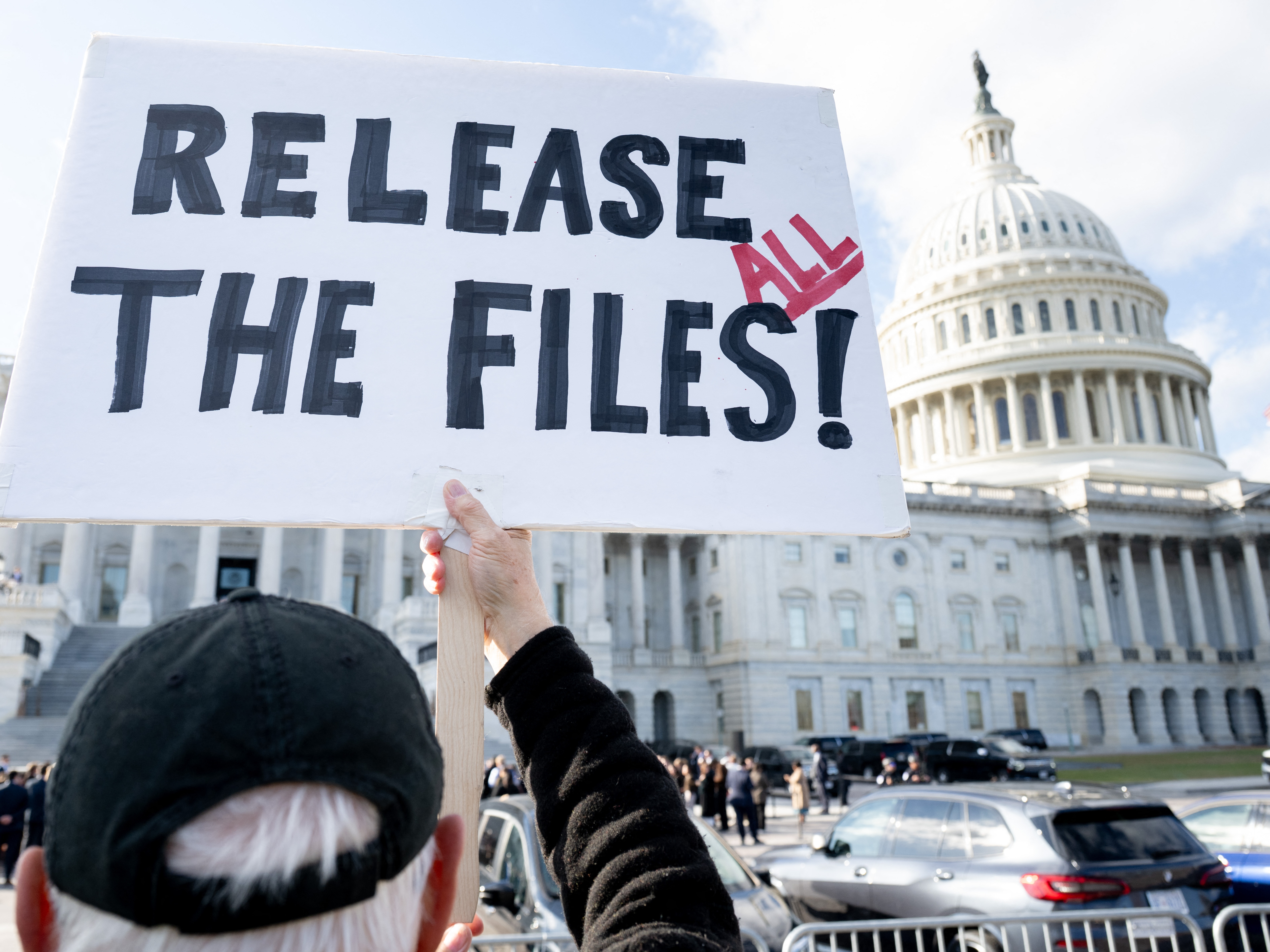 caption: A protester holds a sign related to the release of the Jeffrey Epstein case files outside the U.S. Capitol on November 12, 2025.