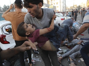 caption: An injured Palestinian boy is carried away in the aftermath of an Israeli airstrike outside the entrance of the al-Shifa hospital in Gaza City on Nov. 3. Israel said it targeted Hamas members using an ambulance to leave the hospital. Hamas denied this. Hospital officials said 13 people were killed and dozens injured.