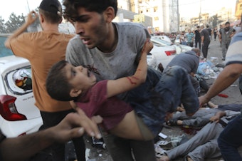 caption: An injured Palestinian boy is carried away in the aftermath of an Israeli airstrike outside the entrance of the al-Shifa hospital in Gaza City on Nov. 3. Israel said it targeted Hamas members using an ambulance to leave the hospital. Hamas denied this. Hospital officials said 13 people were killed and dozens injured.