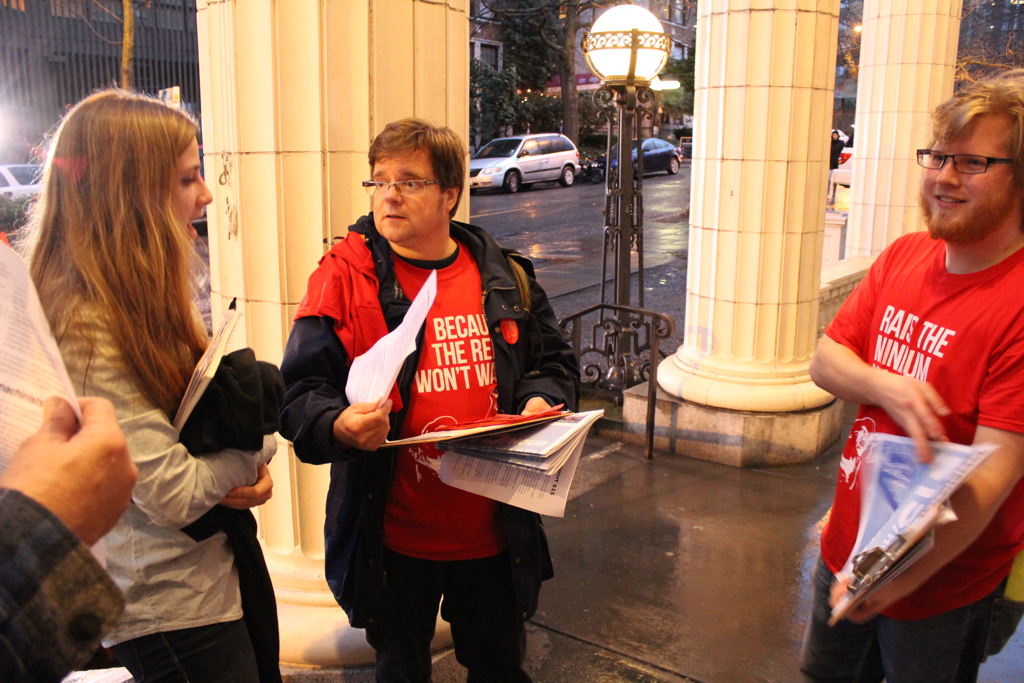 caption: Members of the group 15 Now greet people arriving to testify at the Seattle City Council public hearing on minimum wage on Wednesday, March 6.