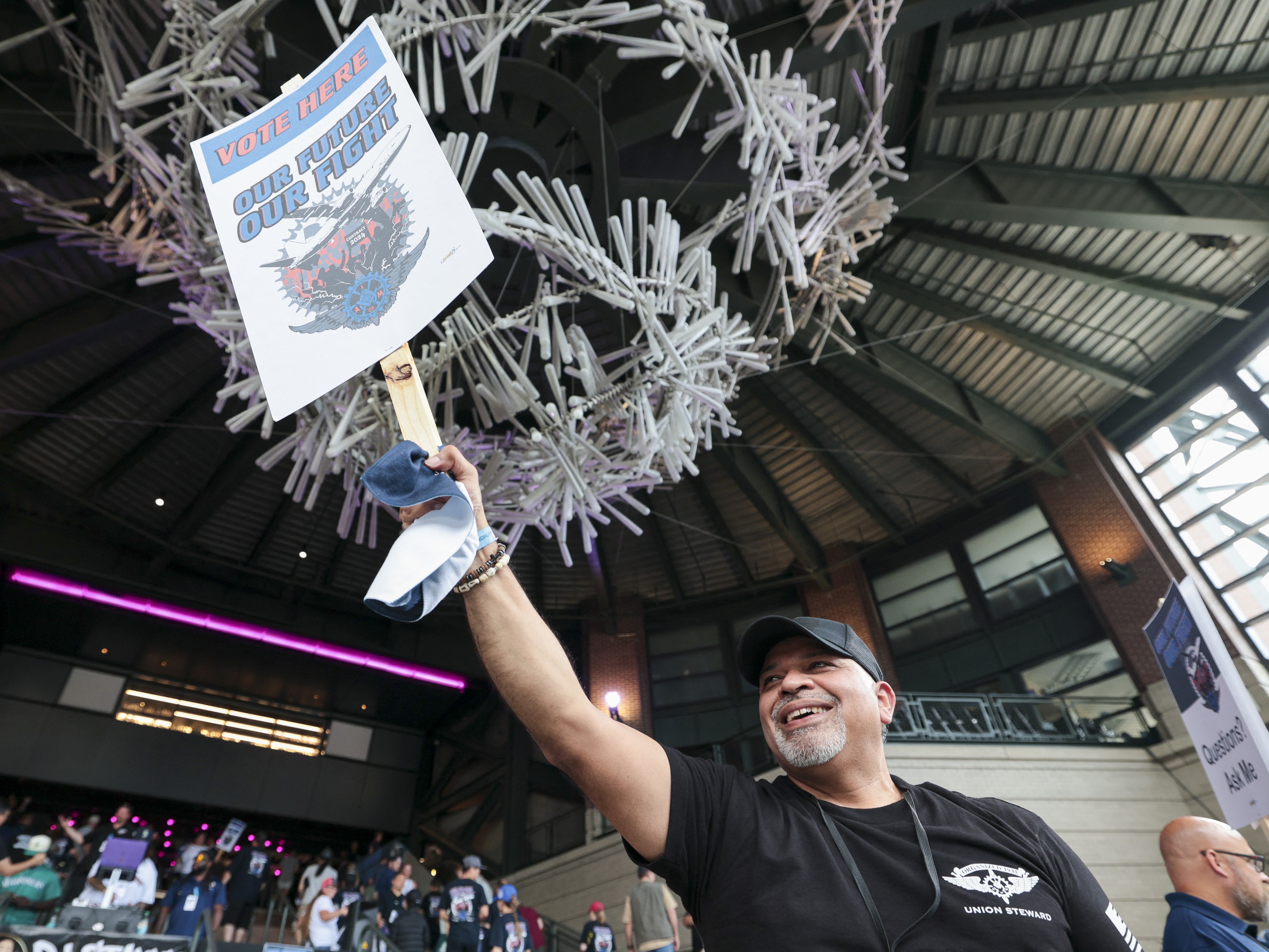 caption: Manny Briones, an iron machinist from Seattle, welcomes members and supporters of the International Association of Machinists and Aerospace Worker Union District 751 for an early strike-sanction vote at T-Mobile Park in Seattle on July 17.