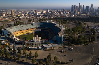 caption: Dodger Stadium in Los Angeles stands empty in an aerial view from late May. Games will resume in late July.