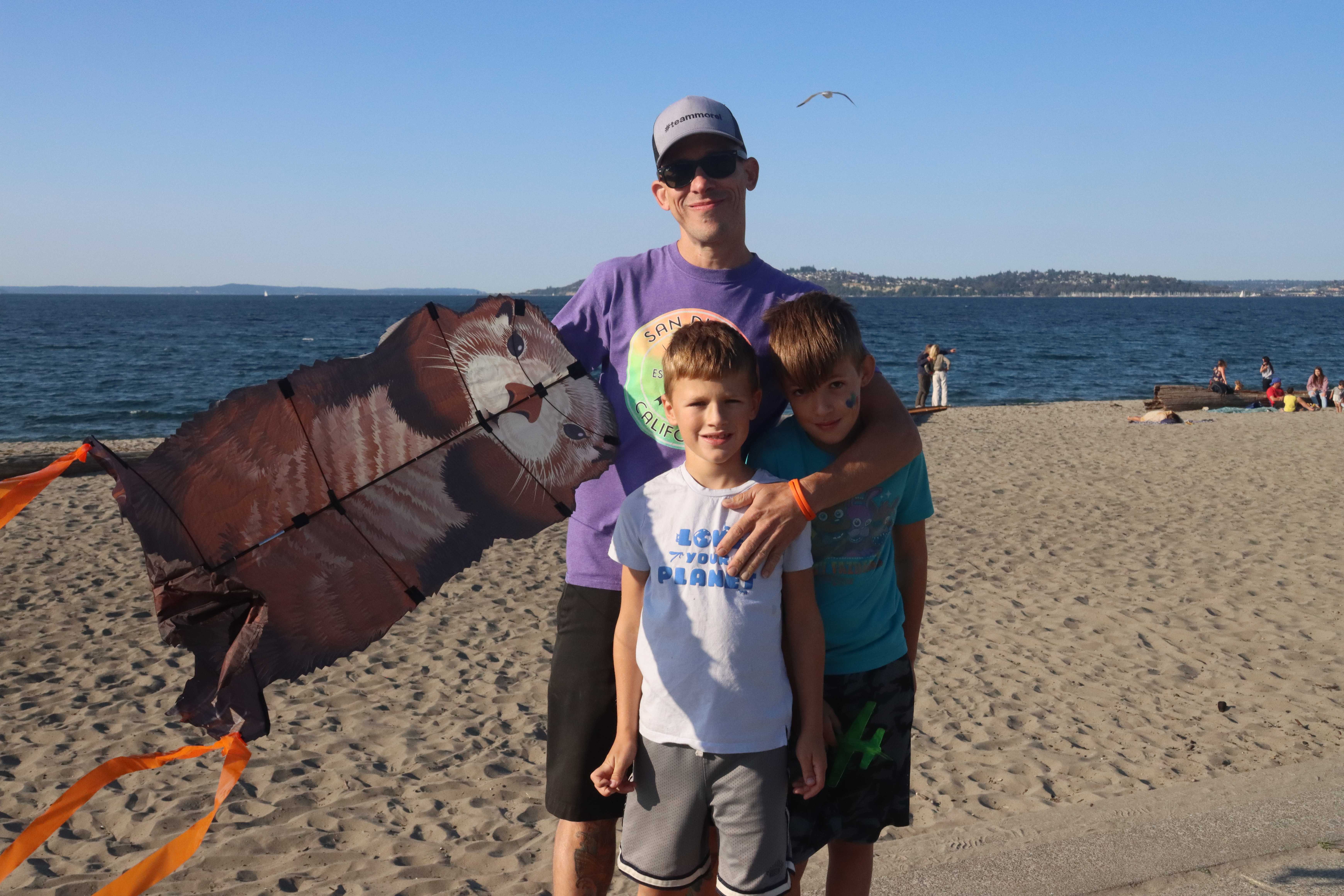 caption: Bill Brown with his kids Noah (left), and Liam (right). They were excited that the West Seattle Bridge reopened so they could visit Alki Beach and use their new kite. 