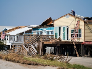 caption: A man works on the roof of a storm-damaged house on Sept. 4 after Hurricane Ida swept through Grand Isle, La. A new poll finds that two-thirds of Americans say if their home is hit by an extreme weather event they'd rather rebuild than relocate.