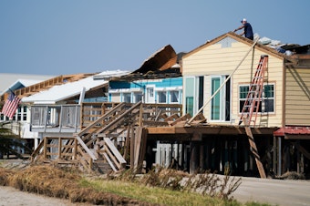 caption: A man works on the roof of a storm-damaged house on Sept. 4 after Hurricane Ida swept through Grand Isle, La. A new poll finds that two-thirds of Americans say if their home is hit by an extreme weather event they'd rather rebuild than relocate.