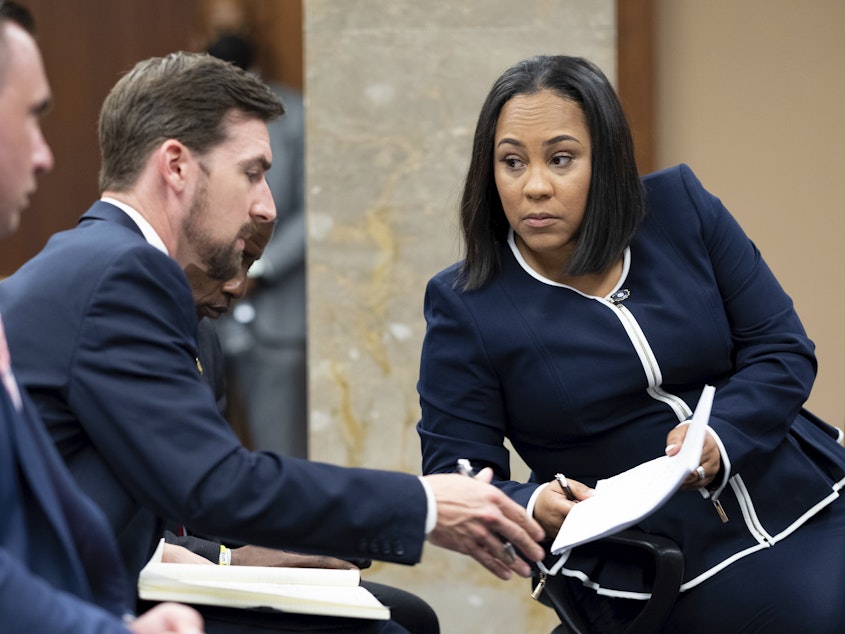 caption: Fulton County District Attorney Fani Willis, right, talks with a member of her team during proceedings to seat a special purpose grand jury in Fulton County, Ga., on Monday