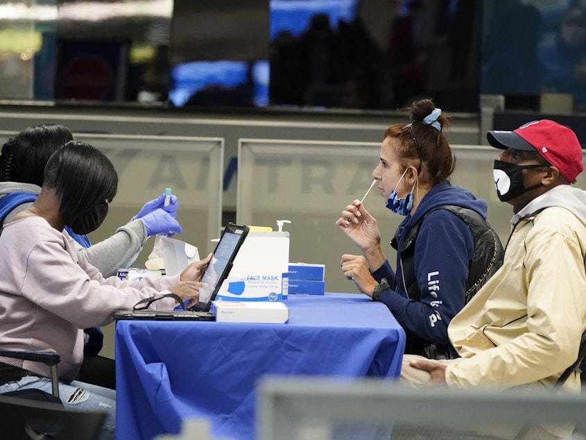 caption: Travelers self-test for the coronavirus at a mobile testing site at New York City's Penn Station in the days leading up to Thanksgiving. The U.S. is currently seeing record hospitalizations for COVID-19, and health experts fear more surges are on their way.