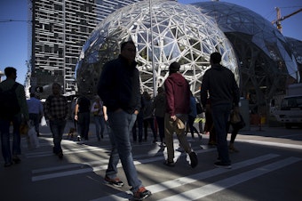 caption: Pedestrians cross the street at Amazon headquarters in Seattle in September. 