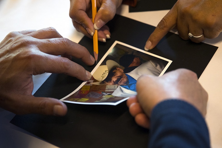 caption: A photograph of Miguel Adame is glued onto a black piece of paper as the Day of the Dead altar is prepared on Tuesday, October 29, 2019, at Casa Latina in Seattle. 