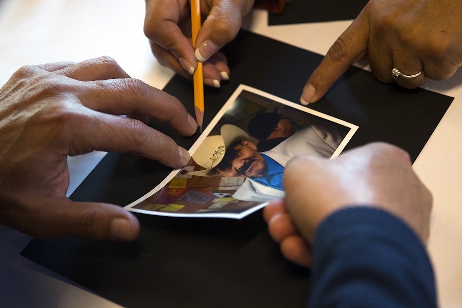 caption: A photograph of Miguel Adame is glued onto a black piece of paper as the Day of the Dead altar is prepared on Tuesday, October 29, 2019, at Casa Latina in Seattle.