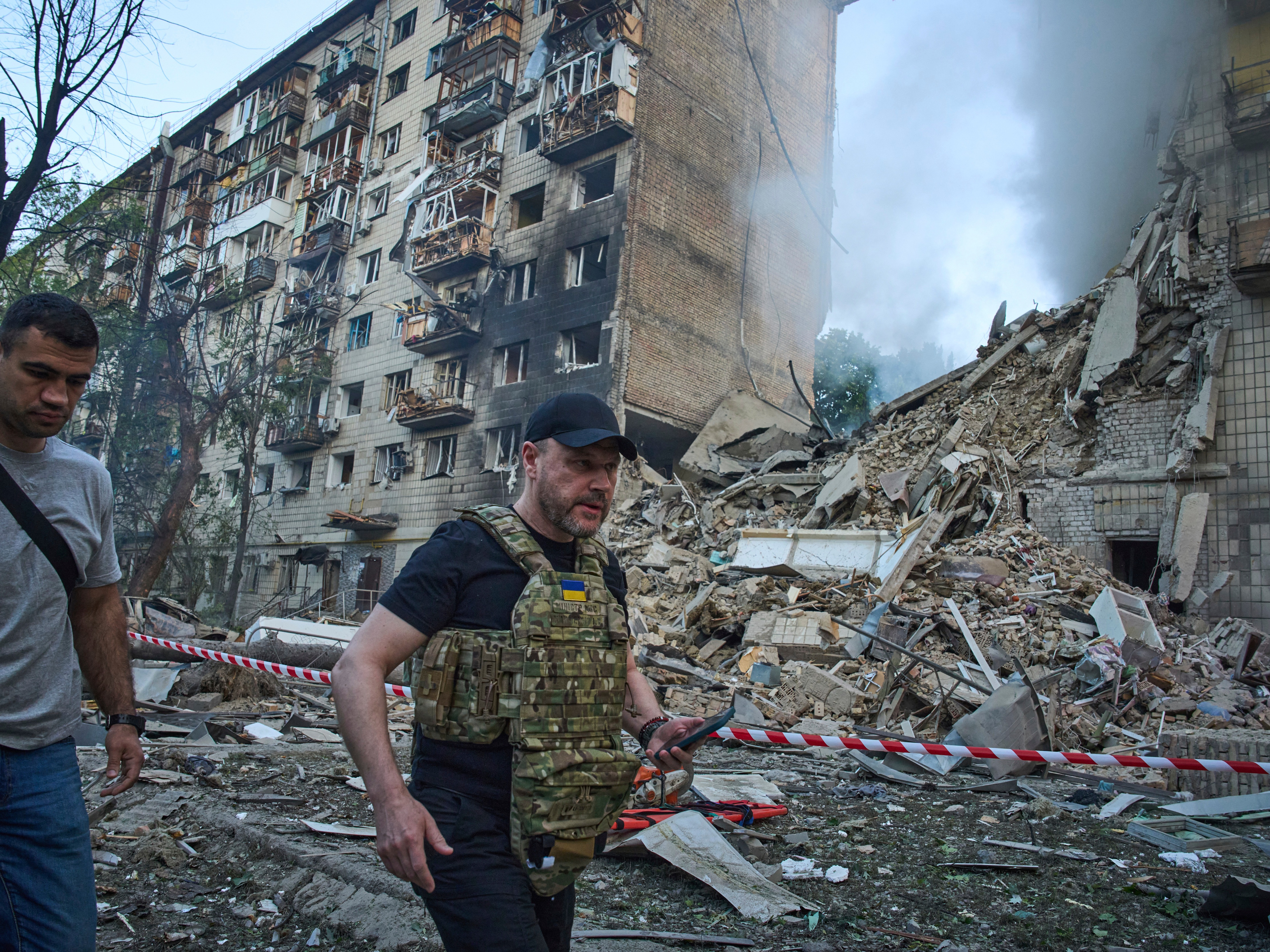 caption: Ukraine Interior Minister Ihor Klymenko, right, examines the site of a missile strike that ruined a residential building during Russia's massive missile and drone air attack in Kyiv, Ukraine, on Tuesday.