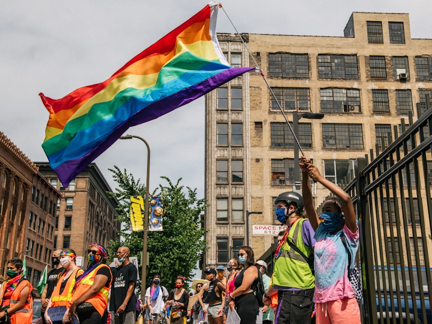 caption: A woman waves a rainbow flag during a Pride march in June 2020 in Minneapolis, Minnesota.
