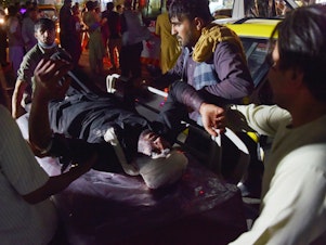 caption: Medical and hospital staff bring an injured man on a stretcher for treatment after two blasts, which killed dozens of people, including U.S. service members, outside the airport in Kabul on Thursday.