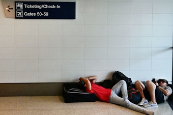 caption: Travelers rest on the ground while waiting for their flights at Los Angeles International Airport on July 1. On Thursday, the U.S. Transportation Department is rolling out a new website that will allow passengers to see what they're legally entitled to when an airline cancels or significantly delays their flight.