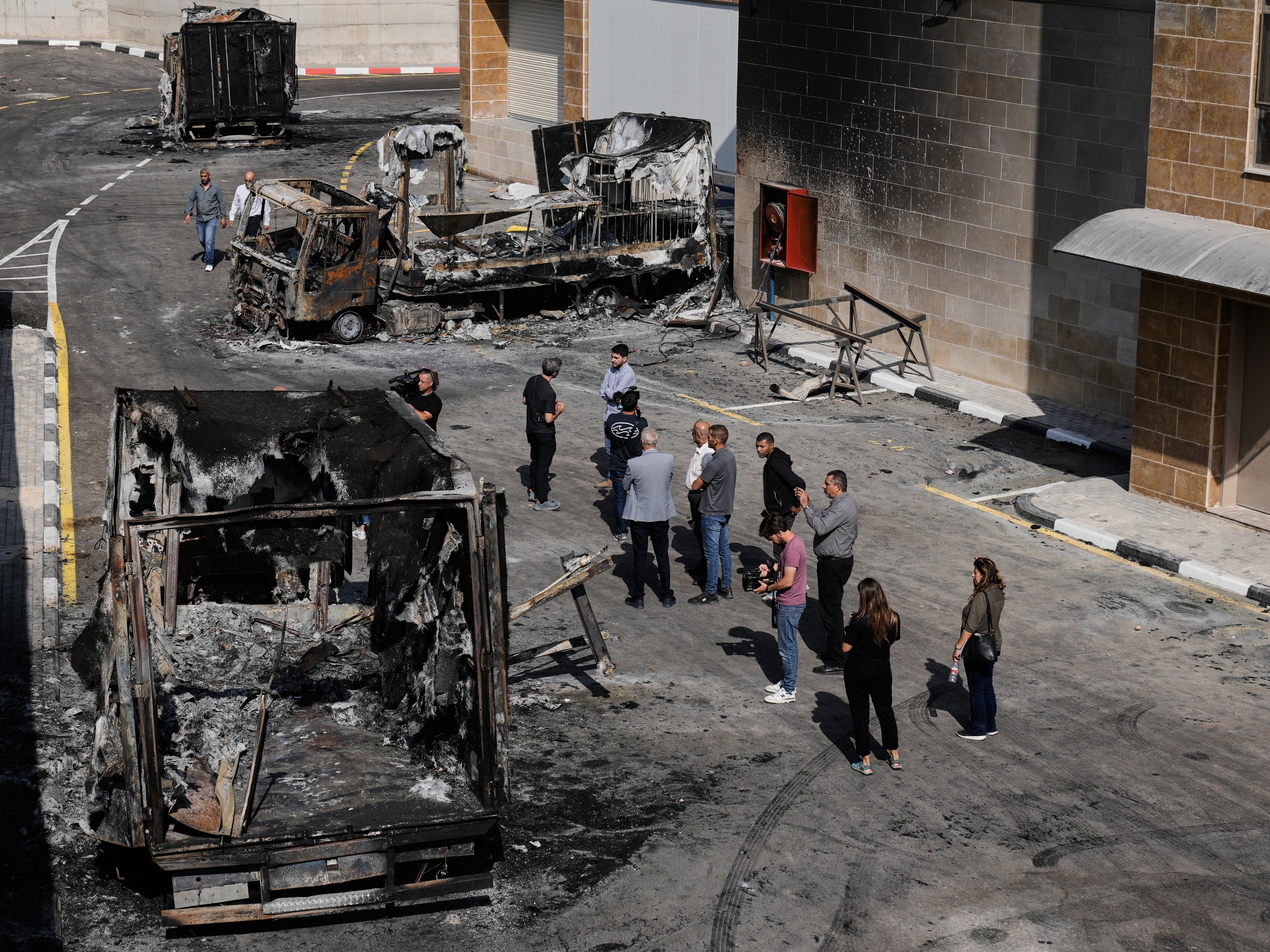 caption: Palestinians and journalists survey damage in an industrial zone following an attack by Israeli settlers the previous day in the West Bank village of Beit Lid, near Tulkarm, Wednesday.