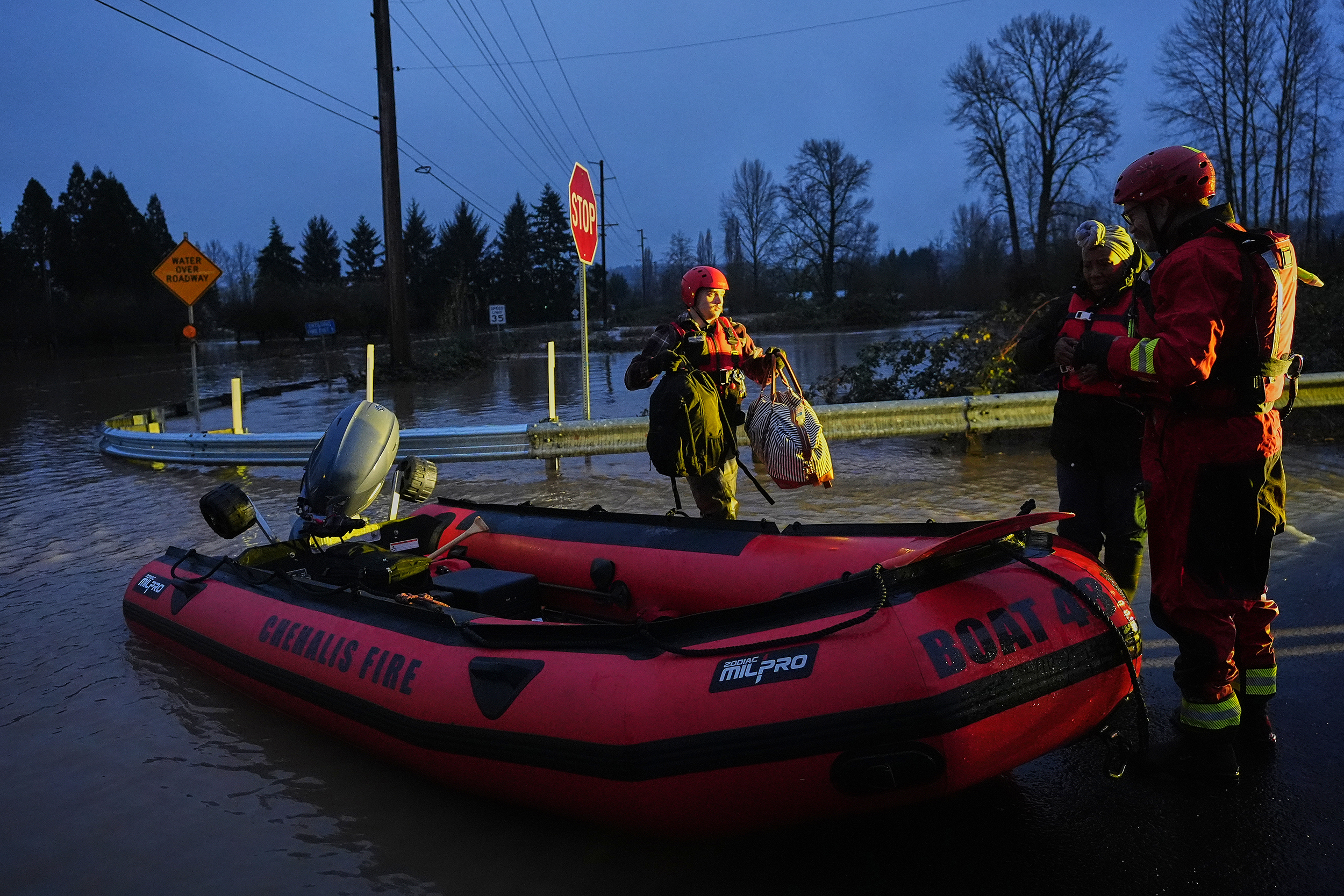 caption: Chehalis Fire rescue workers help residents evacuate their flooded neighborhood after heavy rains in the region Tuesday, Dec. 9, 2025, in Chehalis, Wash. 