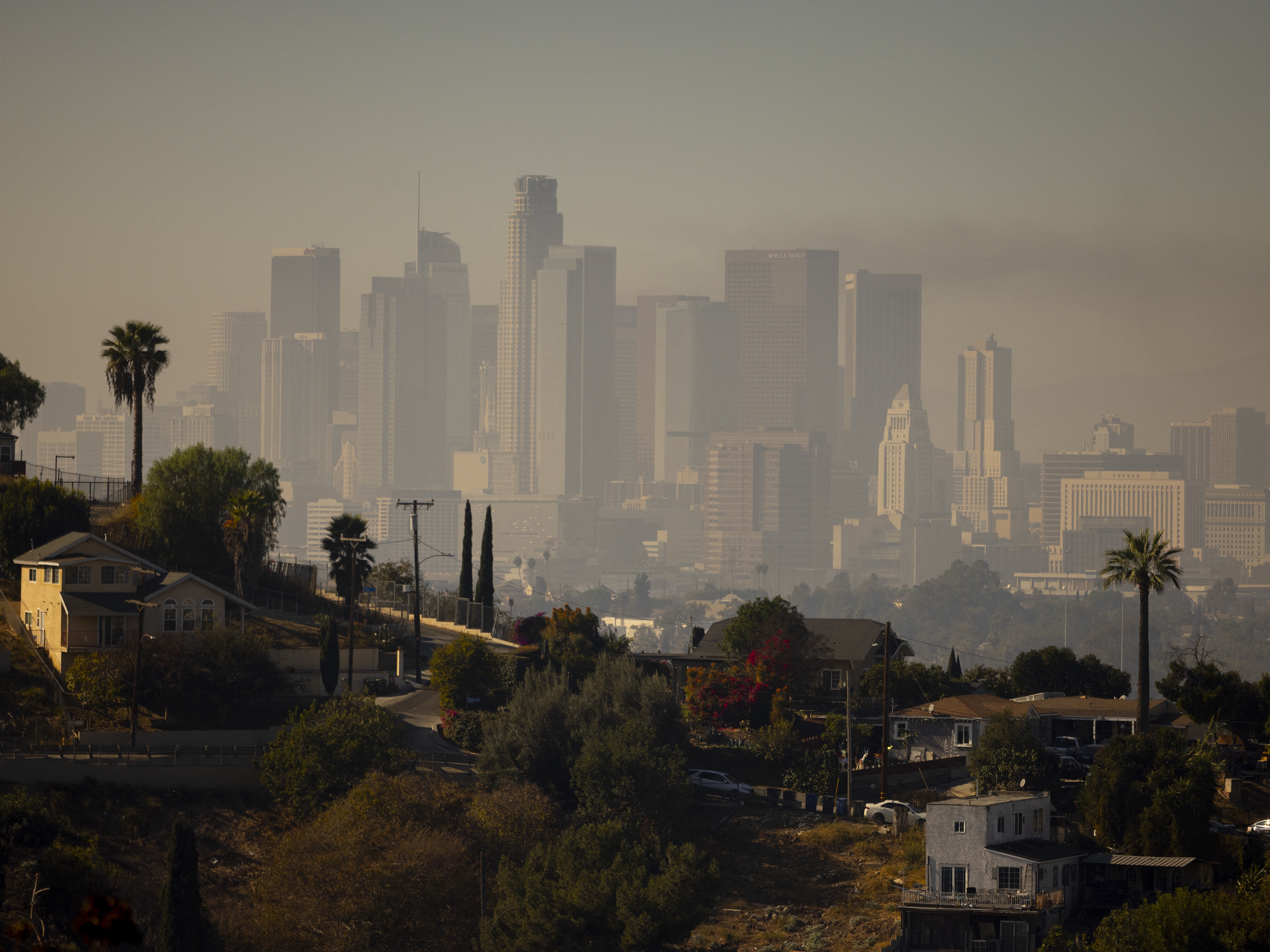 caption: A layer of smog lingers above downtown Los Angeles in 2024. Millions of Americans are still breathing in unhealthy air, despite long-term progress toward cleaning up many sources of pollution, according to the 2025 State of the Air report.