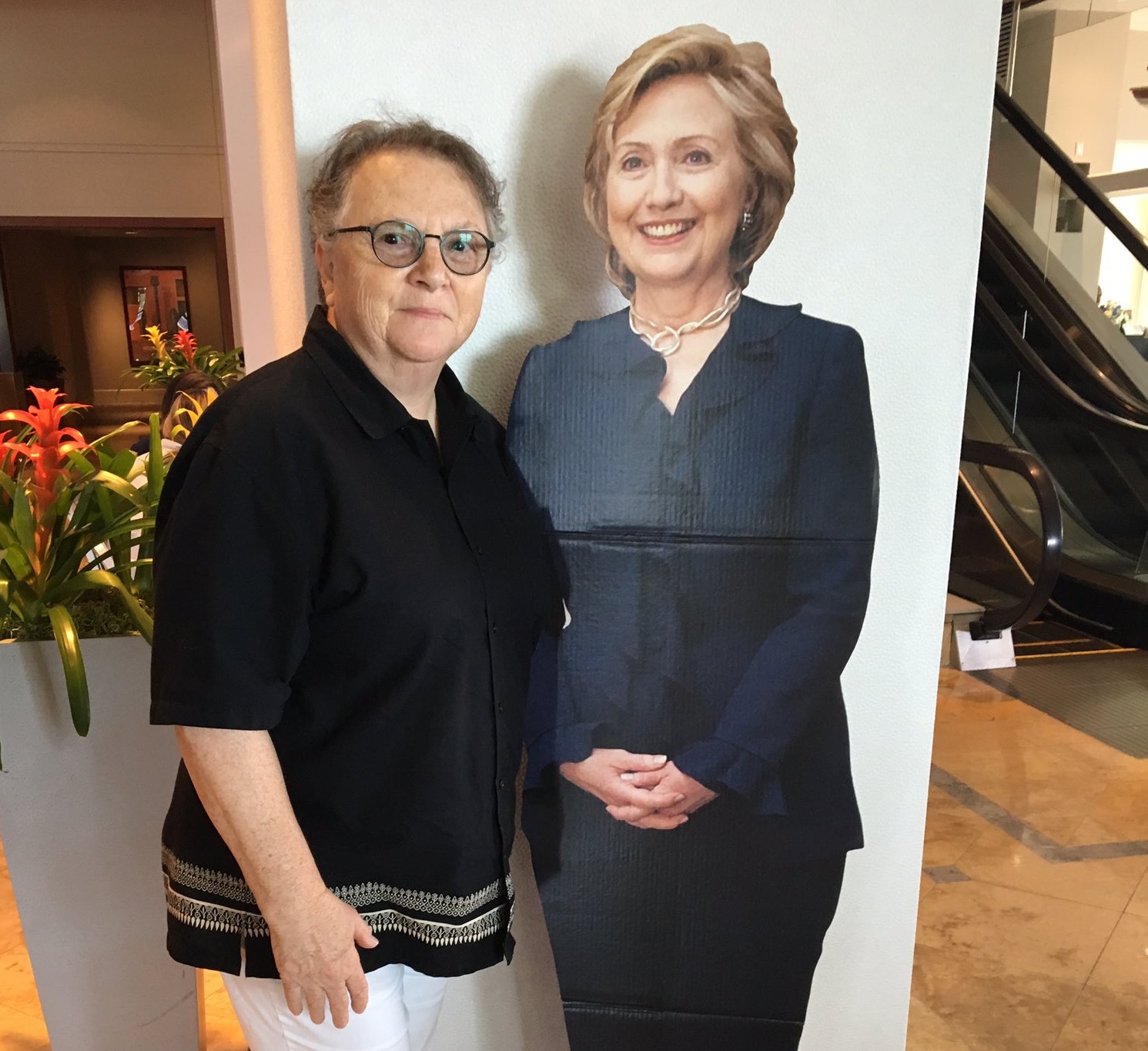 caption: Susan Atlas poses with a cutout of Hillary Clinton at a hotel lobby in Philadelphia on Friday.