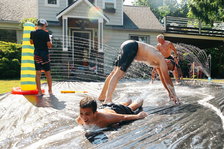 caption: Makis Vouros, 12, slip n' slide under his dad, Vasili, as they hang out with friends in Vouros's front yard in Skyway, Monday, June 28. The National Weather Service recorded 108 degrees in SeaTac on Monday, setting an all-time record for the area. A car temperature gauge recorded 109 degrees in Skyway at 4:30 pm.