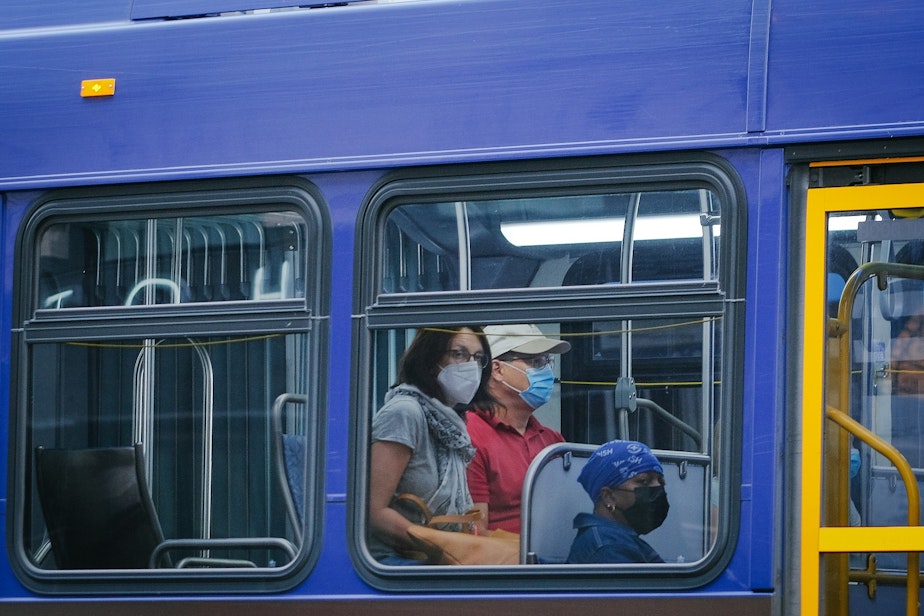 caption: Masked passengers ride the bus through downtown, August 3, 2021. Masks remain a requirement on King County public transit, including busses and street cars.
