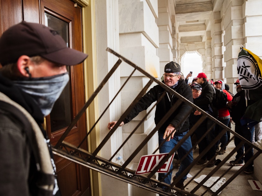 caption: A member of a pro-Trump mob bashes an entrance of the Capitol building in an attempt to gain access on Jan. 6. The U.S. Capitol Police's inspector general has pointed to intelligence failures in the lead-up to the insurrection.