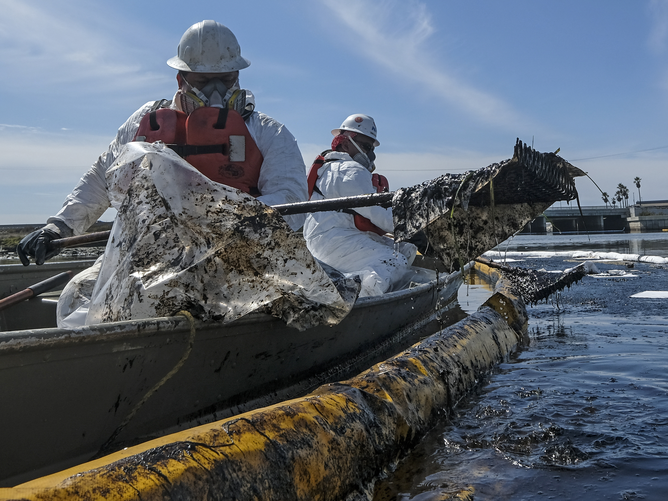caption: Cleanup contractors deploy skimmers and floating barriers known as booms to try to stop further crude oil incursion into Talbert Marsh in Huntington Beach, Calif., on Oct. 3 after an oil spill off the Southern California coast.