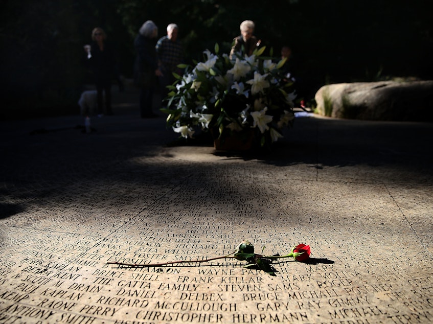 caption: A flower lays on the engraved names of AIDS victims at the National AIDS Memorial Grove on December 1, 2015 in San Francisco, Calif.