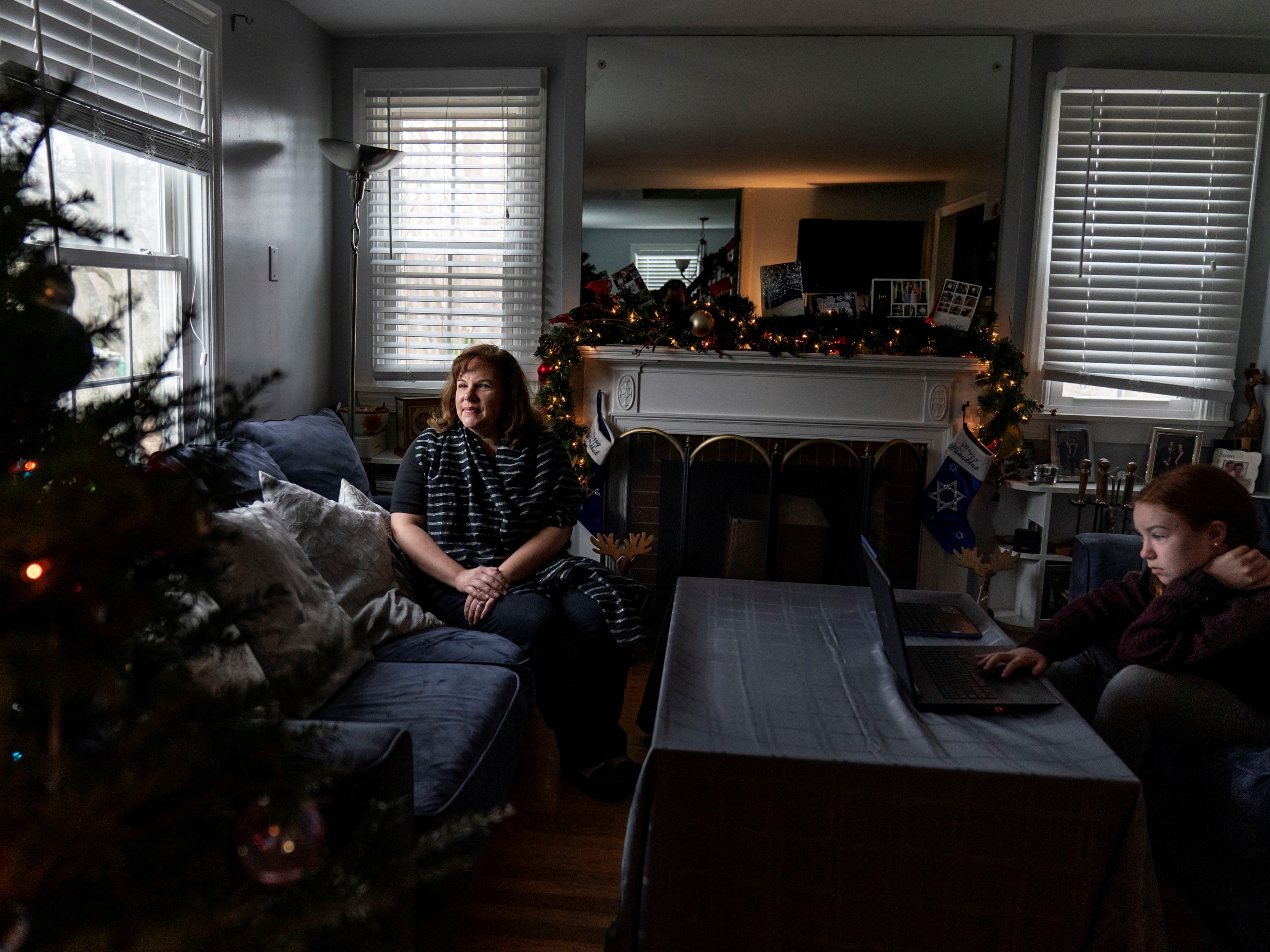 caption: Eileen Carroll, left, sits for a portrait as her daughter, Lily, 11, attends school remotely from their home in Warwick, R.I. on Dec. 16. When Carroll's other daughter tested positive for the coronavirus, state health officials told her to notify anyone her daughter might have been around. Contact tracers, she was told, were simply too overwhelmed to do it.