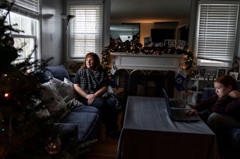 caption: Eileen Carroll, left, sits for a portrait as her daughter, Lily, 11, attends school remotely from their home in Warwick, R.I. on Dec. 16. When Carroll's other daughter tested positive for the coronavirus, state health officials told her to notify anyone her daughter might have been around. Contact tracers, she was told, were simply too overwhelmed to do it.