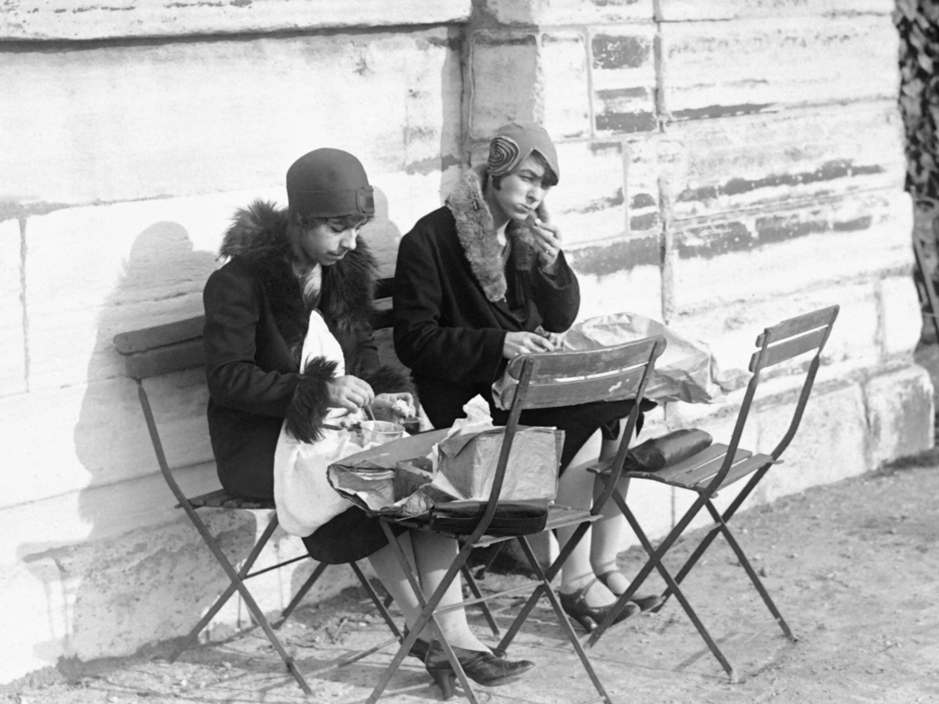 caption: Young women eat lunch in the Tuileries Garden in Paris in January 1929.