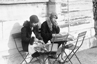 caption: Young women eat lunch in the Tuileries Garden in Paris in January 1929.