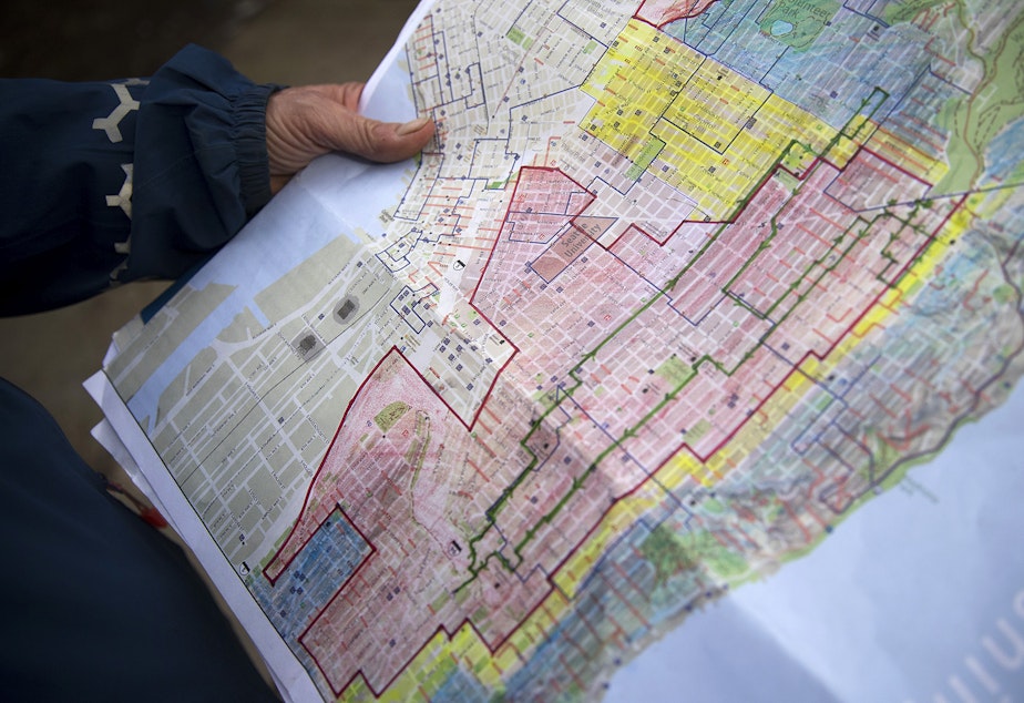 Seattle native Merlin Rainwater holds a map outlining the red line zone on Wednesday, March 7, 2018, in Seattle.