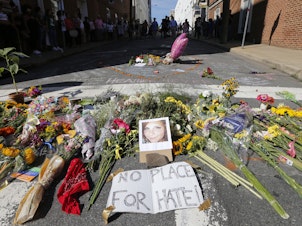 caption: A makeshift memorial of flowers and a photo of victim Heather Heyer sits in Charlottesville, Va., on Aug. 13, 2017. Heyer died when a car rammed into a group of people who were protesting white supremacists who had gathered in the city for a rally.