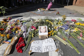 caption: A makeshift memorial of flowers and a photo of victim Heather Heyer sits in Charlottesville, Va., on Aug. 13, 2017. Heyer died when a car rammed into a group of people who were protesting white supremacists who had gathered in the city for a rally.