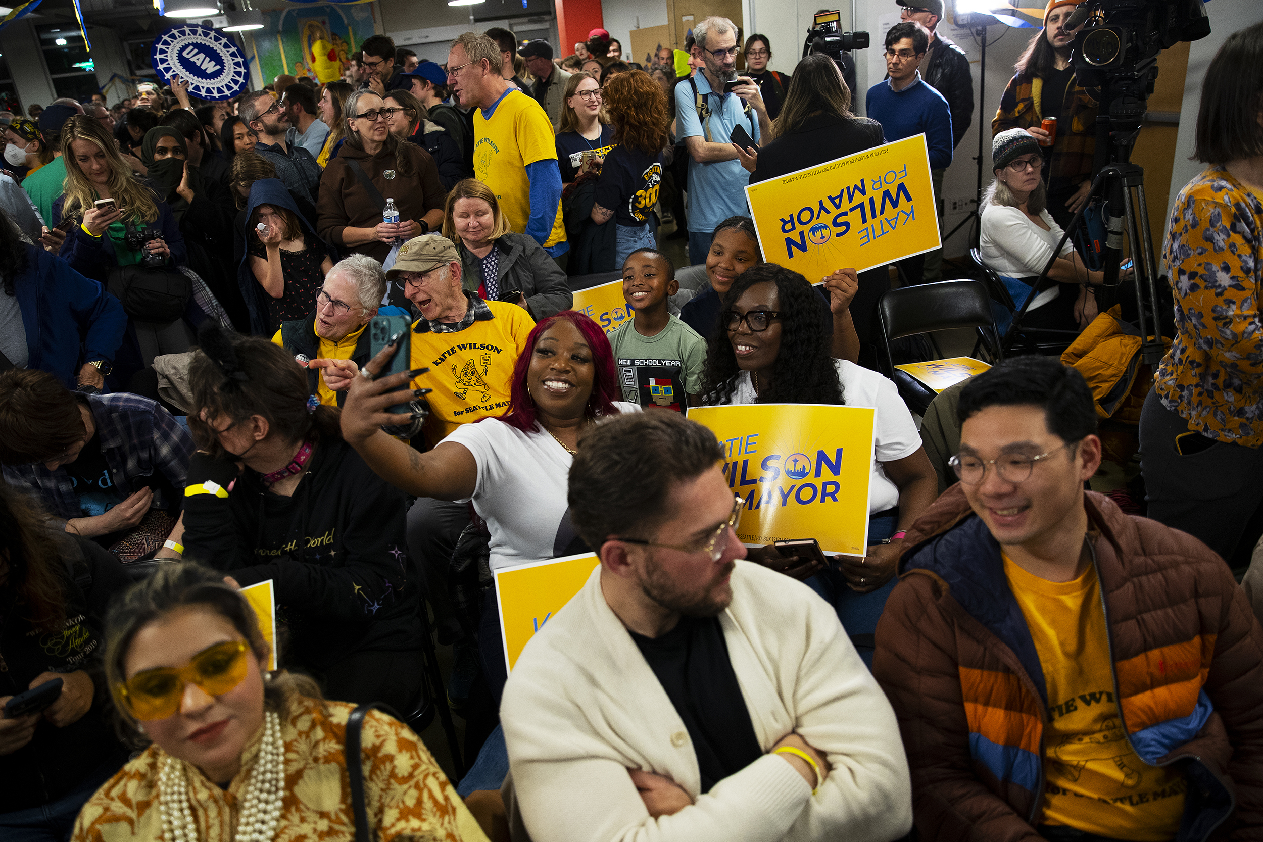 caption: Supporters of city of Seattle mayoral candidate Katie Wilson take selfies before she speaks on Tuesday, November 4, 2025, at El Centro de la Raza in Seattle. 