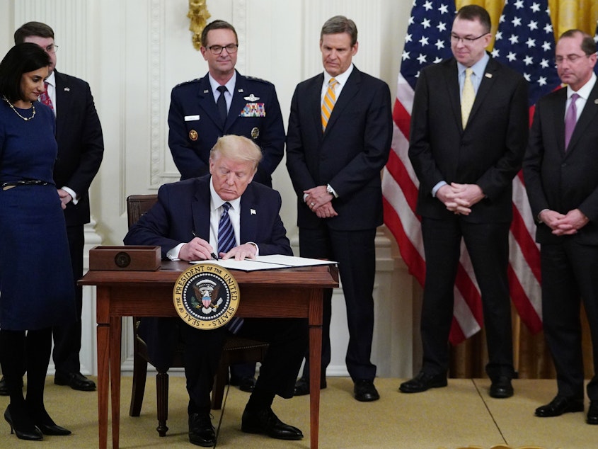 caption: President Trump, surrounded by federal officials on Thursday, signs a proclamation for Older Americans Month during an event on protecting seniors from the coronavirus.