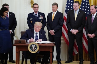 caption: President Trump, surrounded by federal officials on Thursday, signs a proclamation for Older Americans Month during an event on protecting seniors from the coronavirus.